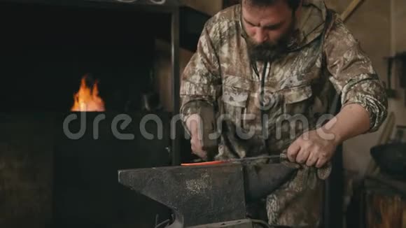 年轻铁匠在传统铁匠的铁砧上手工锻造铁刀视频的预览图