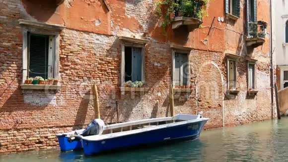 一座威尼斯砖房紧挨着一艘停着的小船经过一条运河另一条船上有人视频的预览图