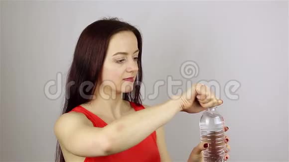 美丽的年轻女子打开瓶子喝水视频的预览图