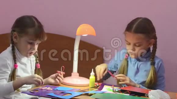 女孩看起来像另一个女孩的蝴蝶结棒从彩色纸板上剪下来视频的预览图