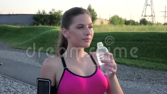 健身妇女在公园室外从塑料水中喝淡水慢动作视频的预览图