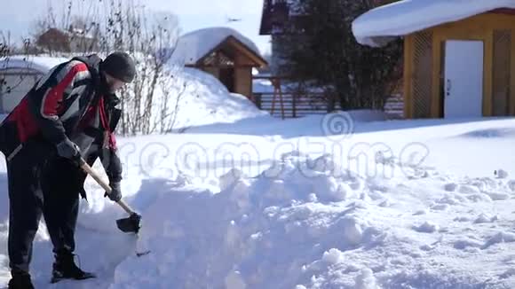 一个手里拿着铲子的人从房子附近的雪上清理小径高清1920x1080下面的动作视频的预览图