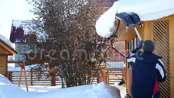 一个人屋顶上的大型雪堆清理铲子高清1920x1080视频的预览图