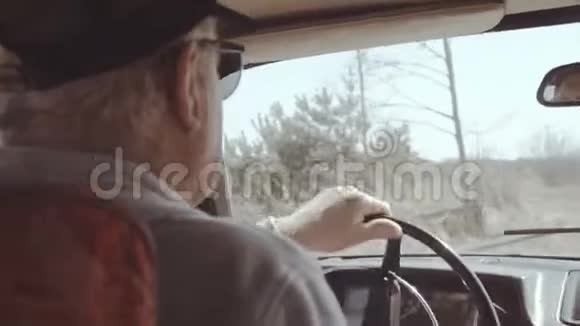 在非城市道路上老人乘坐复古车的后视角视频的预览图
