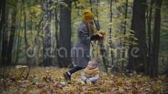 幸福的家庭观念小女儿和妈妈在秋天的森林里玩黄叶慢动作视频的预览图