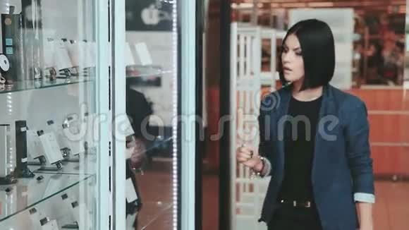 购物年轻的黑发女人经过商店橱窗附近的配件小工具视频的预览图
