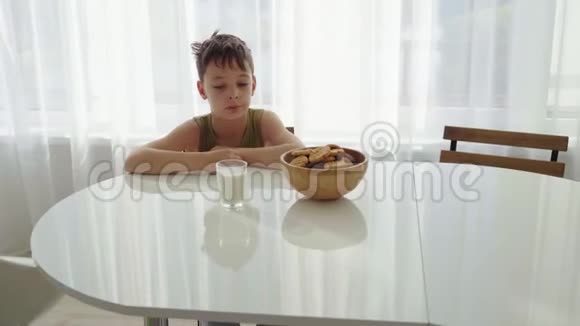 男孩在家厨房吃自制的带牛奶的饼干视频的预览图