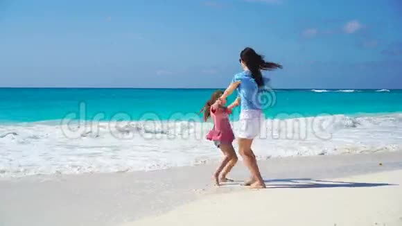 在热带海滩上可爱的小女孩和年轻的母亲两个家庭在暑假里玩得很开心视频的预览图