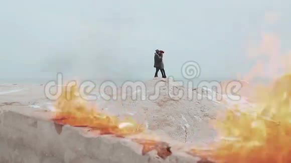 一对夫妇站在火的背景下在沙滩上冬天的大海视频的预览图