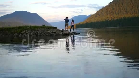 在日落时分情侣在河边散步视频的预览图