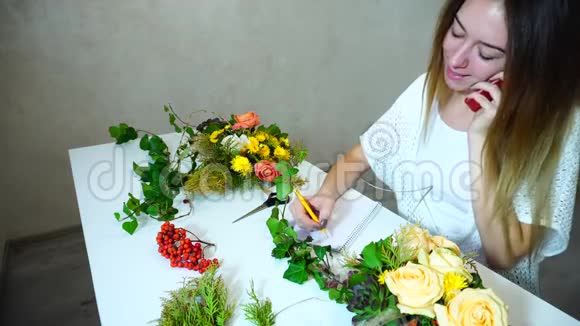 漂亮的女花设计师在电话里接受插花的订单白天坐在明亮的办公室里视频的预览图
