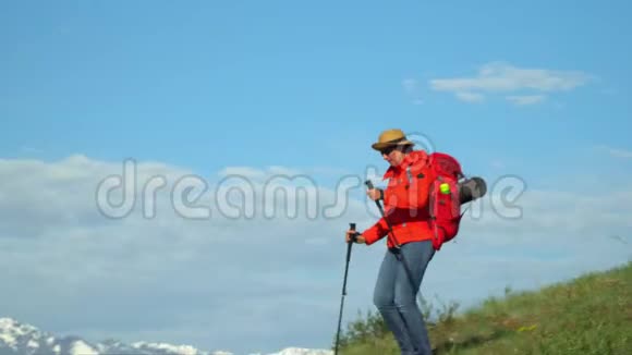 旅行者的女人用棍子爬上山坡进行追踪红色背包用于追踪的棍子视频的预览图