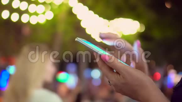 那个女人手里拿着智能手机在夜城的街道上城市中使用智能手机的亲密女性视频的预览图