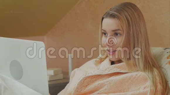 使用笔记本电脑的专注女性躺在病床上进行视频聊天视频的预览图