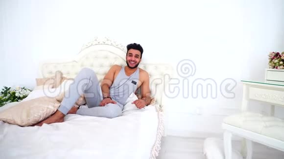 男性穆斯林度假者从城市喧嚣的床上在明亮的卧室的肖像视频的预览图