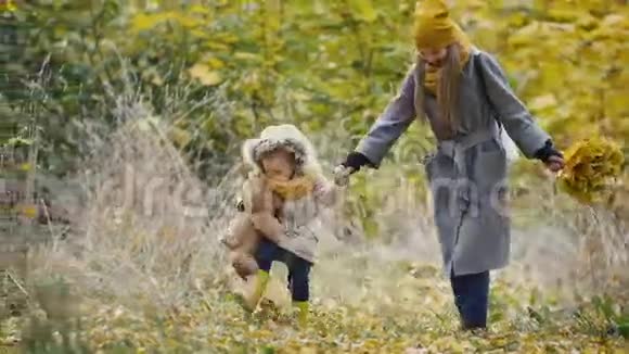 妈妈和她的女儿在一个秋天的公园里玩耍妈妈给孩子拿着一个她的酒吧踢黄色的视频的预览图
