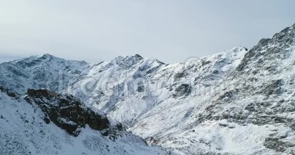 前方鸟瞰冬季雪山岩峰落基山脉的山顶覆盖着冰雪冰川视频的预览图