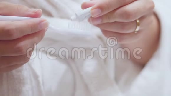 美丽的黑发将牙膏的基础铺在牙刷上年轻的女人刷牙视频的预览图