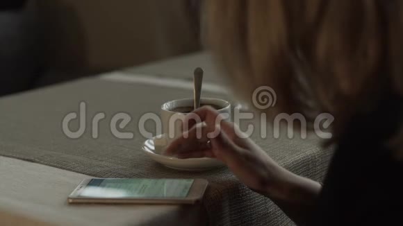 女人手在背景咖啡杯上的屏幕手机上输入信息视频的预览图