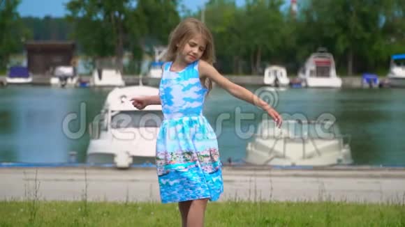 这位金发姑娘在码头上的一块草坪上转了个弯可爱的小女孩带着一个大视频的预览图