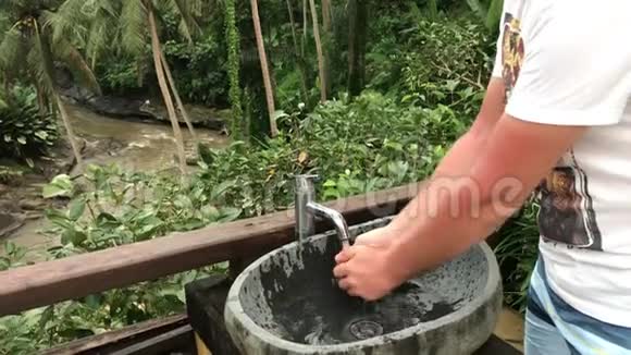 男人在外面洗手带着美丽的热带景色新鲜度和生态理念巴厘岛视频的预览图