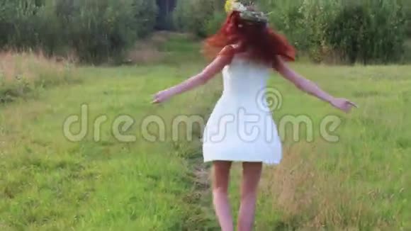 夏夜戴着花环的漂亮女人在森林附近的草地上旋转视频的预览图