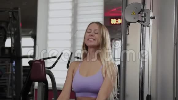 一位身材优美的运动女性在健身房的街区模拟器上训练腿和臀部视频的预览图