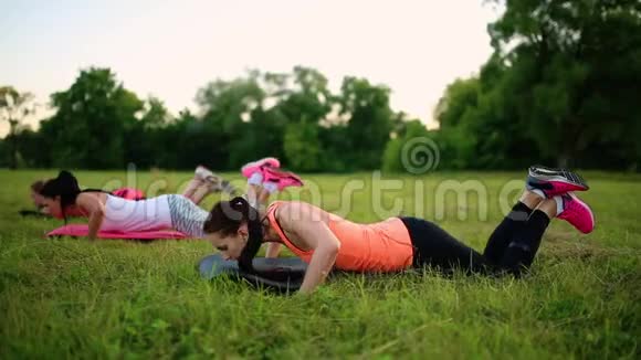 三个女人正在公园的草地上做俯卧撑视频的预览图