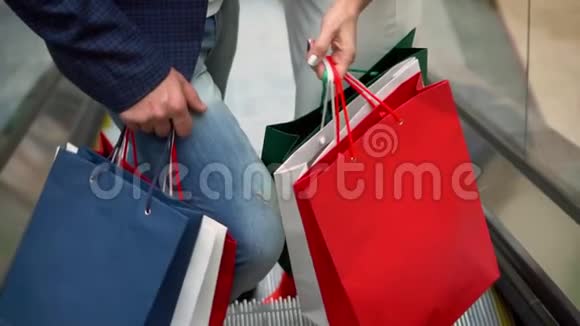 购物中心自动扶梯上的买家携带购物套餐那个男人和女人一起爬上扶梯视频的预览图