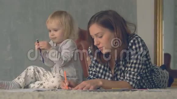 妈妈和她的小女儿用铅笔在相册里画画视频的预览图