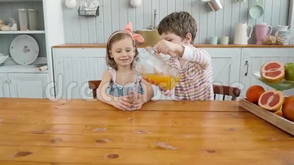男孩哥哥为孩子们提供橙汁女孩姐姐在厨房家庭幸福视频的预览图