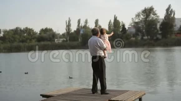 祖父和孙女在湖边散步视频的预览图