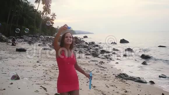 日落时分快乐的黑发女人在热带海滩上玩肥皂泡慢动作1920x1080视频的预览图