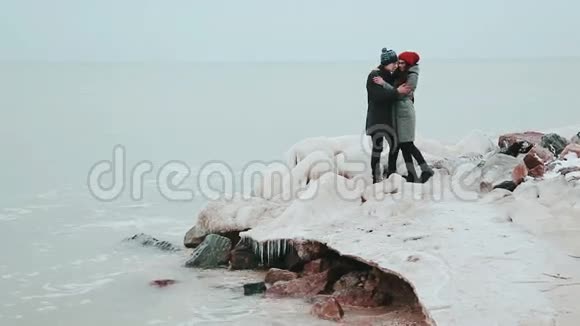 冰石岭年轻的一对夫妇站在冬天的海边视频的预览图