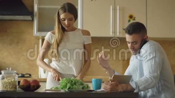 一对漂亮的夫妇一大早就在厨房里美丽的女孩一边做早餐一边和男朋友聊天视频的预览图