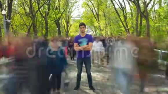 男子站在鬼魅般的人群流背景上绿树成荫时光流逝摄像机正在接近视频的预览图