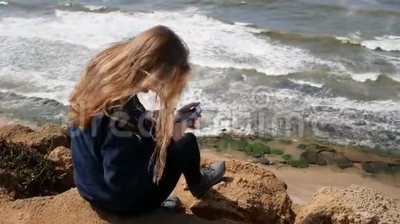金发女孩正拿着智能手机站着视频的预览图