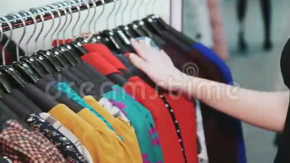 女人手横穿一架衣服在精品店里浏览视频的预览图