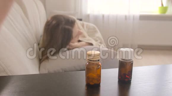从床头柜取药瓶中取药的年轻病妇特写镜头视频的预览图