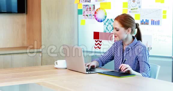 会议室内使用笔记本电脑和平板电脑的女平面设计师视频的预览图