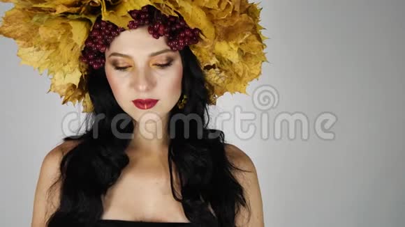 美丽的黑头发姑娘在画室里挂着鲜艳的秋叶花圈视频的预览图