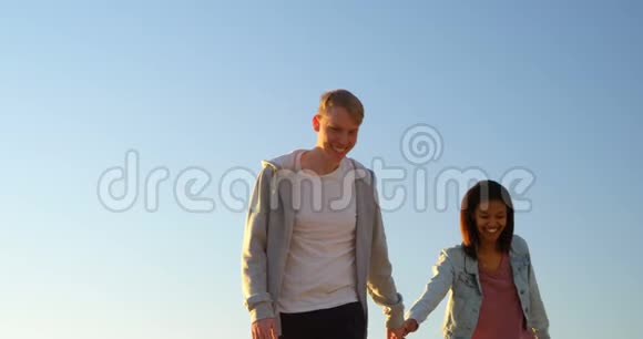 幸福的年轻夫妇手牵手在海滩上散步视频的预览图
