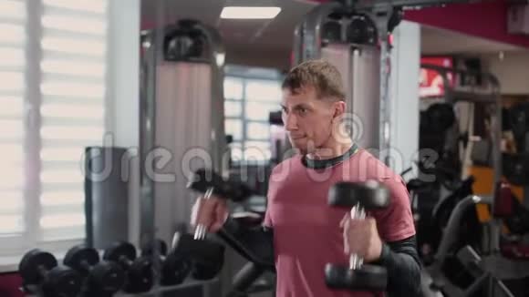 英俊的运动员在健身房训练哑铃二头肌视频的预览图