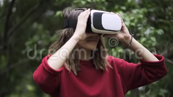 穿红衣服的女孩在公园里戴着VR眼镜视频的预览图