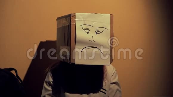晚上的女孩戴着一个盒子头上画着一张不开心的脸悲伤和不幸的概念4KUHD60至视频的预览图