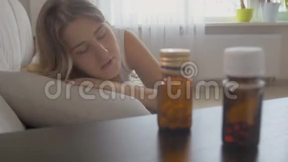 年轻女子感到恶心用床头柜里的药拿着容器视频的预览图