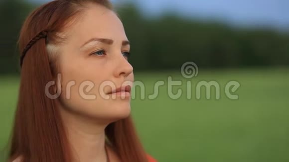 晚上一个红发的年轻美女站在一片绿麦子的田野里把麦穗放在她的地里视频的预览图