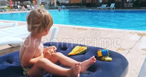 快乐的小男孩坐在游泳池附近视频的预览图