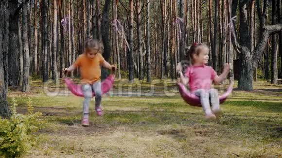 可爱的女孩在森林里玩五颜六色的秋千视频的预览图