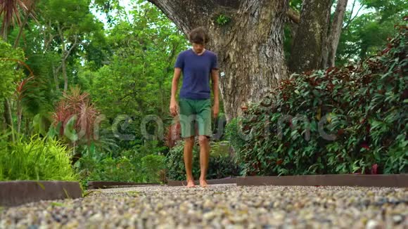 在热带公园里走在反射性道路上的年轻人视频的预览图